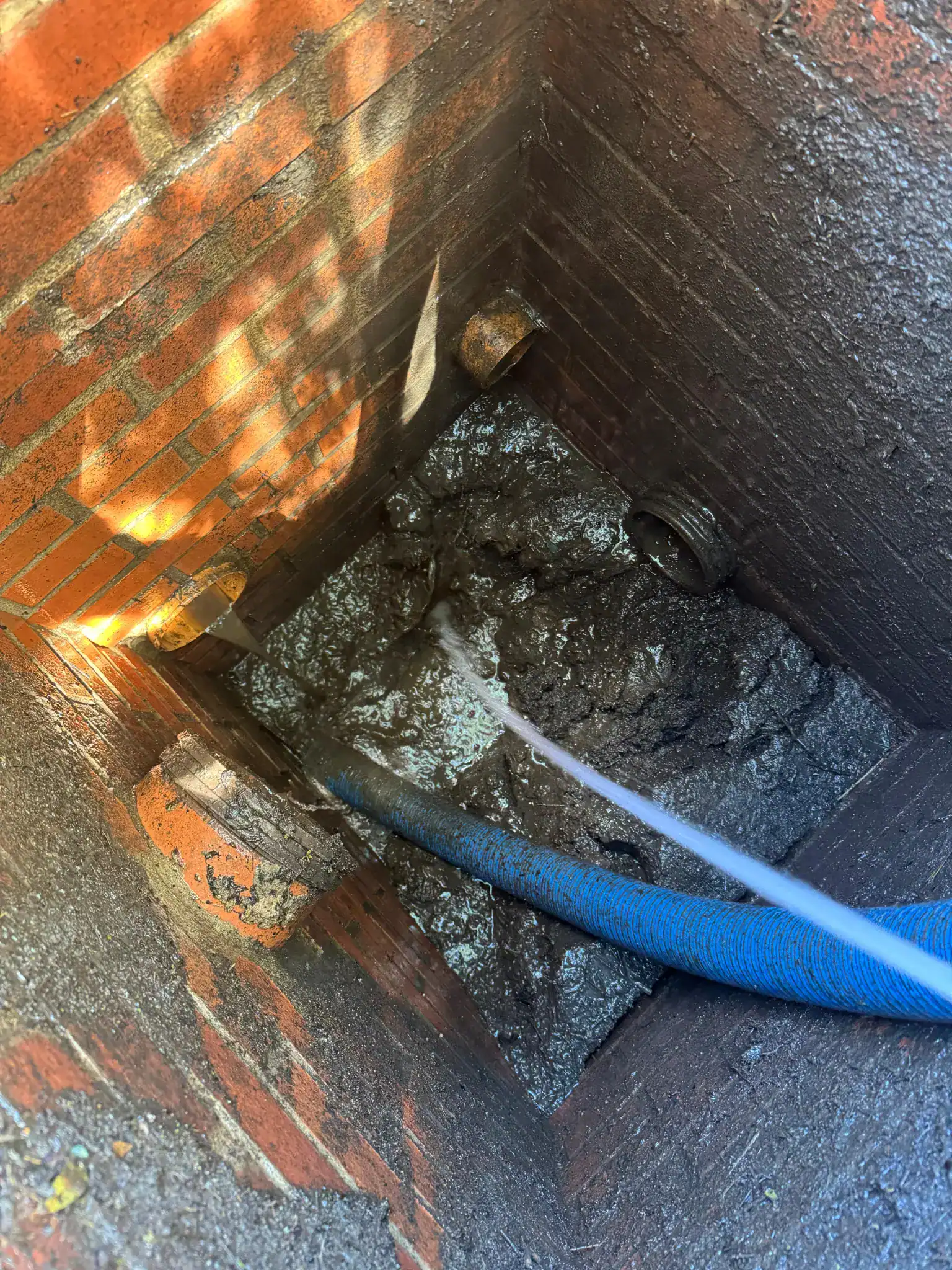 High pressure water jetting King’s Lynn drainage chamber, with a suction hose removing loosened sludge and wastewater.
